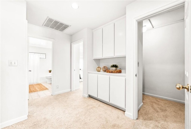 corridor featuring baseboards, visible vents, and light colored carpet