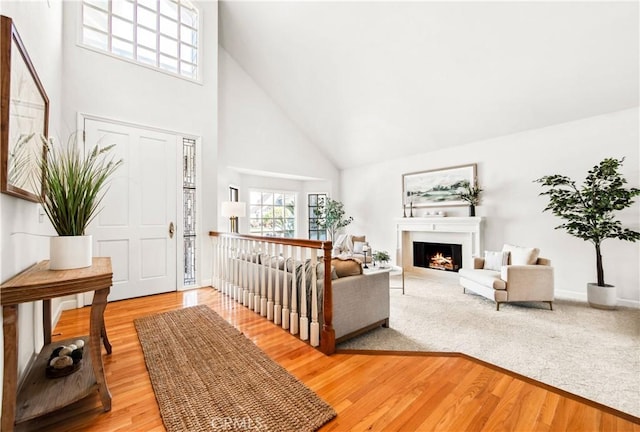 entrance foyer with a lit fireplace, a high ceiling, and wood finished floors