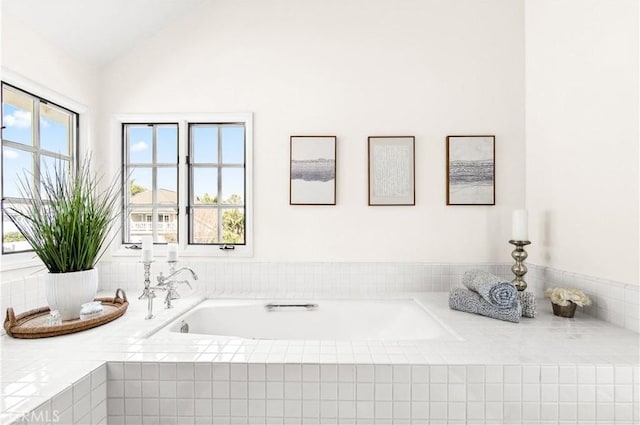 bathroom with lofted ceiling and tiled tub