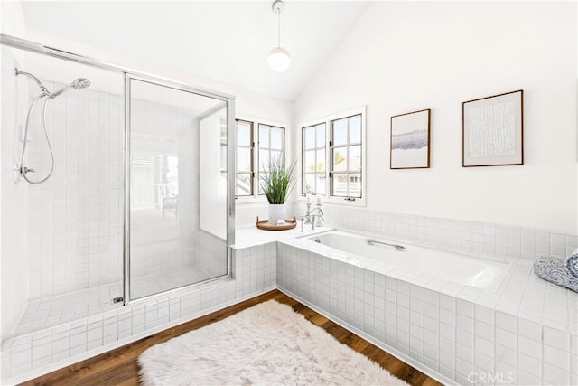 full bathroom with a stall shower, a garden tub, vaulted ceiling, and wood finished floors