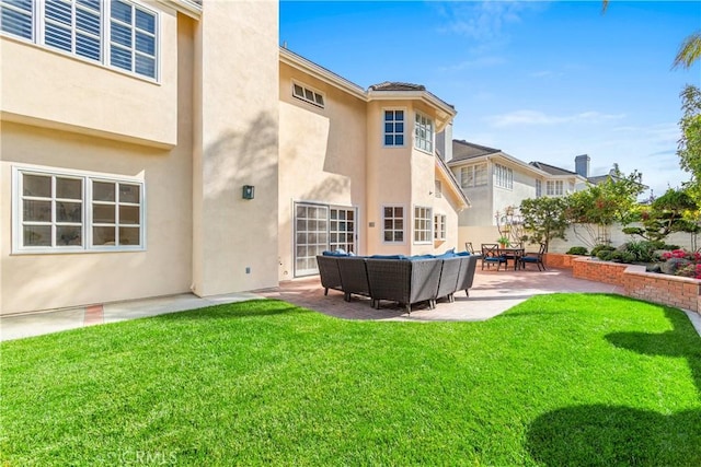 back of house with a lawn, fence, a patio area, outdoor lounge area, and stucco siding