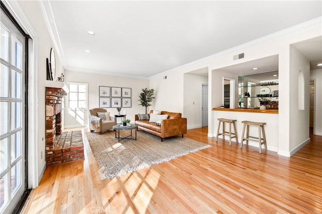 living area with light wood-style floors, arched walkways, ornamental molding, and baseboards