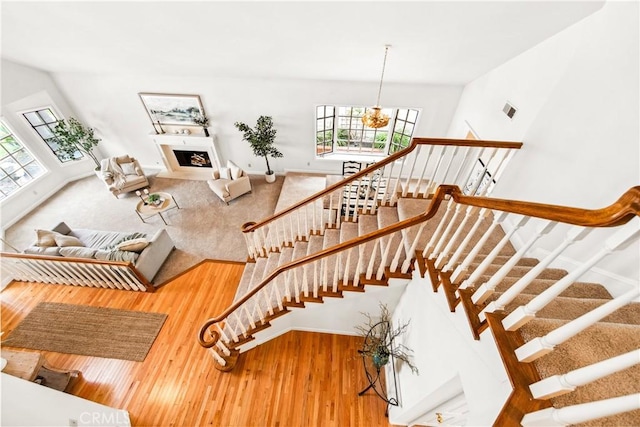 staircase with a notable chandelier, a fireplace, and wood finished floors