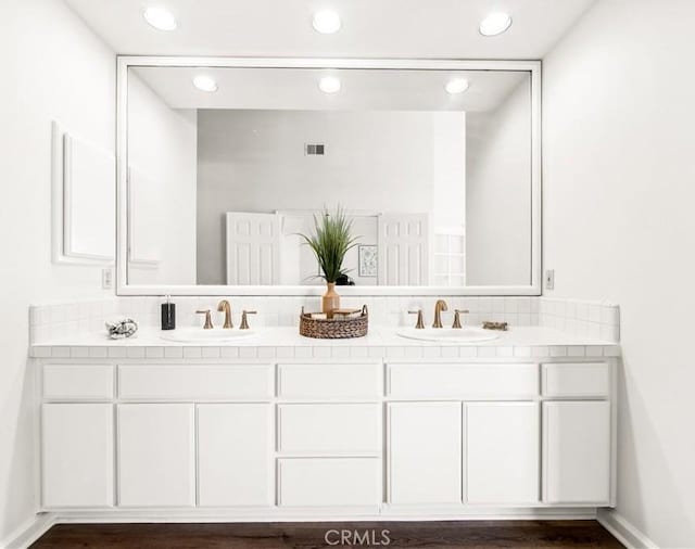 bathroom with double vanity, a sink, visible vents, and baseboards