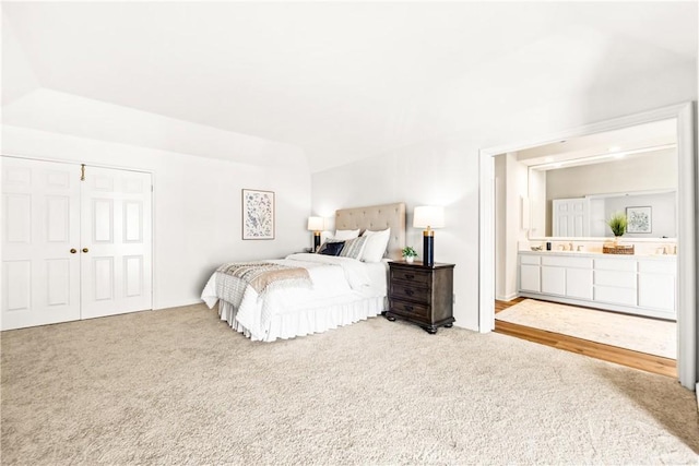 bedroom featuring ensuite bath, a closet, vaulted ceiling, and carpet flooring