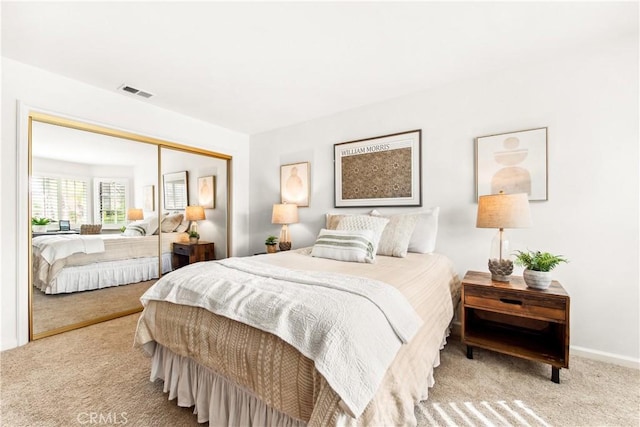 carpeted bedroom with a closet, visible vents, and baseboards