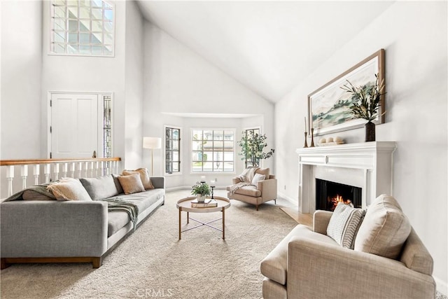 carpeted living room featuring a lit fireplace and high vaulted ceiling