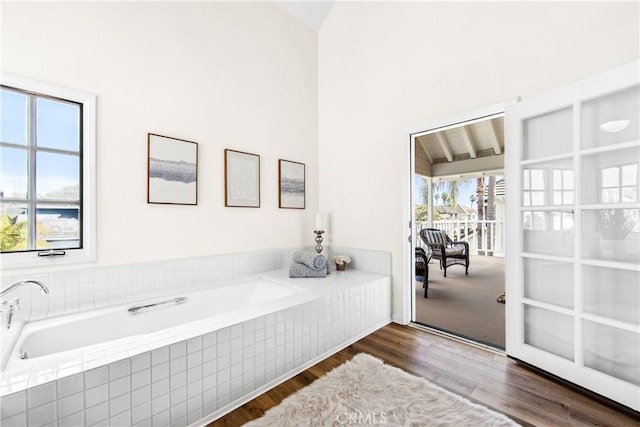 bathroom featuring tiled tub and wood finished floors