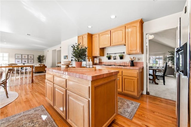 kitchen with tile countertops, a center island, light brown cabinetry, light wood-style floors, and recessed lighting