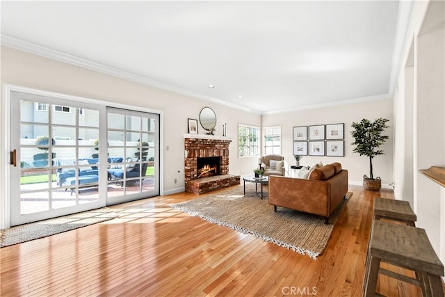 living room with ornamental molding, light wood-type flooring, a fireplace, and baseboards