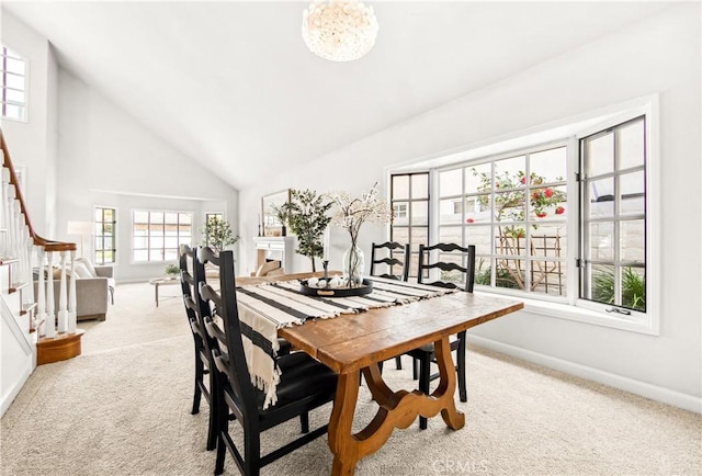 dining space with high vaulted ceiling, a notable chandelier, light carpet, baseboards, and stairway