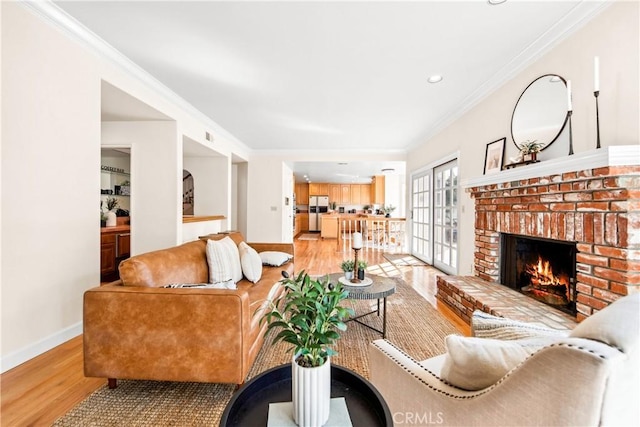 living area featuring ornamental molding, light wood finished floors, a fireplace, and baseboards