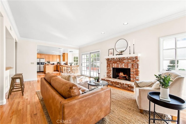 living area featuring ornamental molding, a brick fireplace, light wood-style flooring, and baseboards