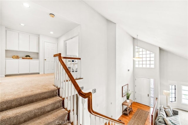 stairs with a healthy amount of sunlight, high vaulted ceiling, carpet floors, and recessed lighting