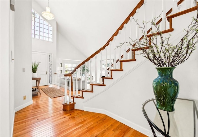 entrance foyer with stairway, plenty of natural light, wood finished floors, and a towering ceiling