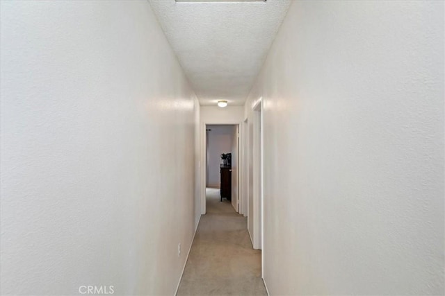 corridor featuring light colored carpet and a textured ceiling