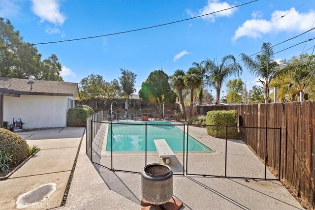 view of pool with a diving board and a patio area