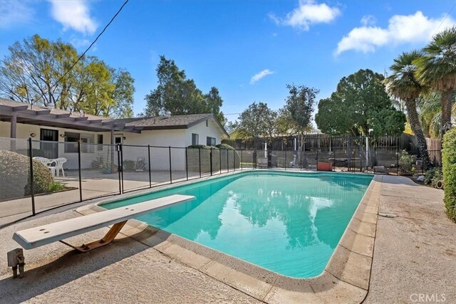 view of swimming pool with a patio area and a diving board