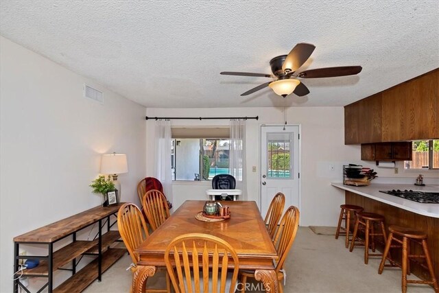 dining room with a wealth of natural light, light colored carpet, and a textured ceiling