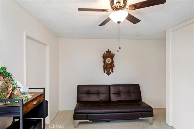 sitting room featuring light carpet, ceiling fan, and a textured ceiling