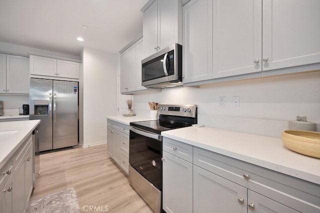 kitchen with appliances with stainless steel finishes and light hardwood / wood-style flooring