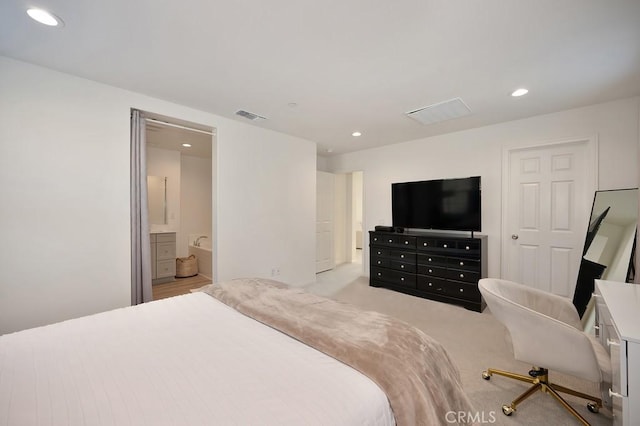 bedroom featuring light carpet and ensuite bathroom