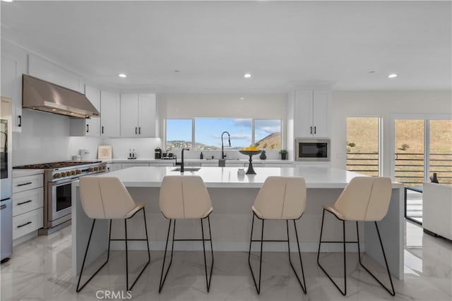 kitchen with white cabinetry, appliances with stainless steel finishes, a center island with sink, and a kitchen breakfast bar