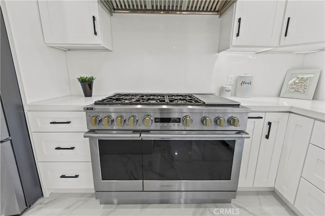 kitchen with white cabinetry, exhaust hood, stainless steel range, and refrigerator