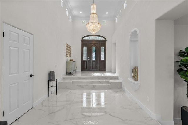 entryway with a high ceiling, ornamental molding, and a chandelier