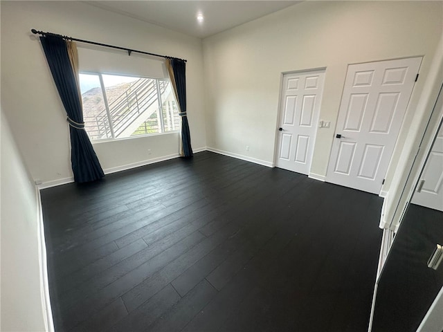 unfurnished room with dark wood-type flooring