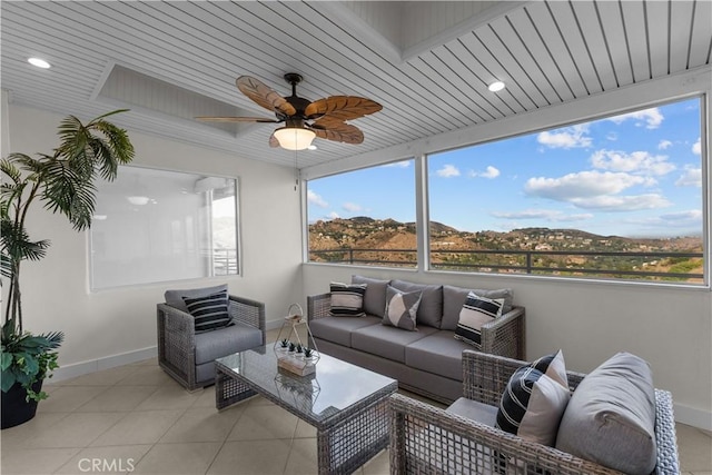 sunroom / solarium with a mountain view, wood ceiling, and ceiling fan