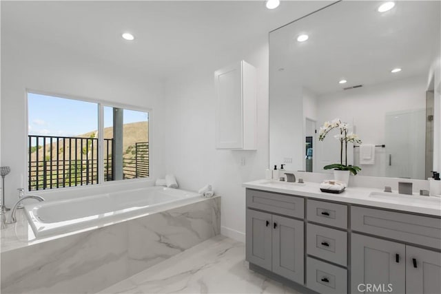 bathroom with vanity and a relaxing tiled tub