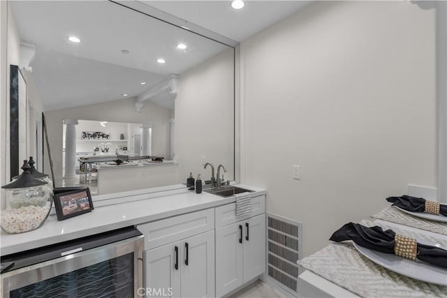 bar featuring white cabinetry, lofted ceiling, beverage cooler, and sink