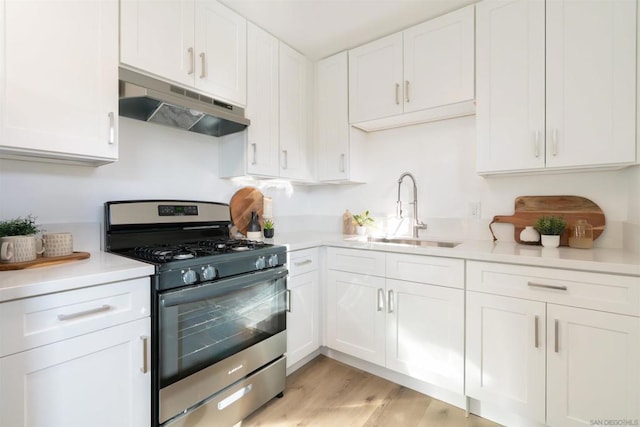 kitchen featuring gas range, white cabinetry, sink, and light hardwood / wood-style flooring