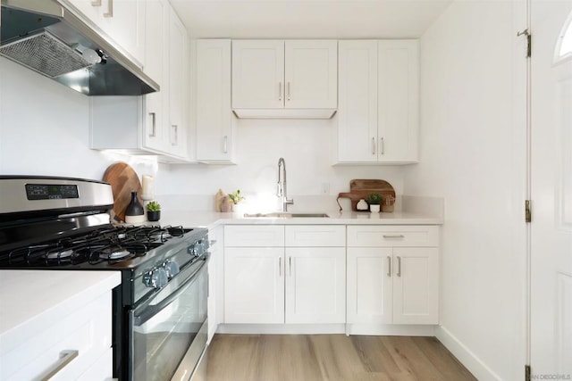 kitchen featuring white cabinetry, sink, extractor fan, and stainless steel gas range oven