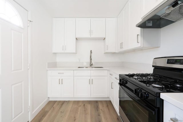 kitchen featuring sink, white cabinetry, range hood, range with gas stovetop, and light wood-type flooring