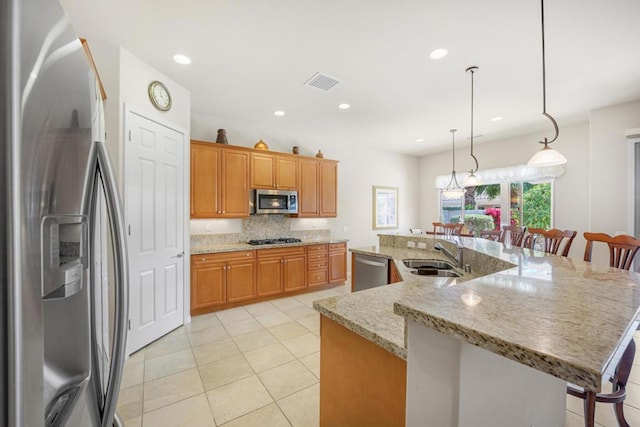 kitchen with appliances with stainless steel finishes, a breakfast bar, and an island with sink