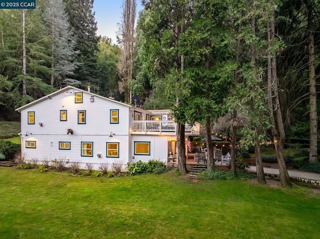 rear view of house featuring a wooden deck and a lawn