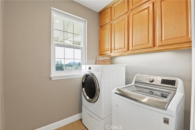 washroom featuring independent washer and dryer, cabinets, and light tile patterned flooring