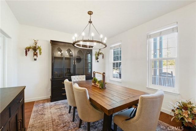 dining space with dark wood-type flooring and an inviting chandelier