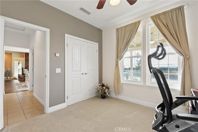 exercise area with light colored carpet and ceiling fan