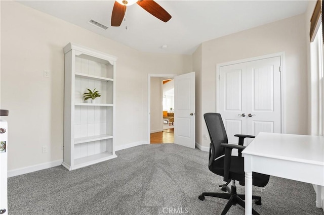 home office featuring light colored carpet, ceiling fan, and built in shelves