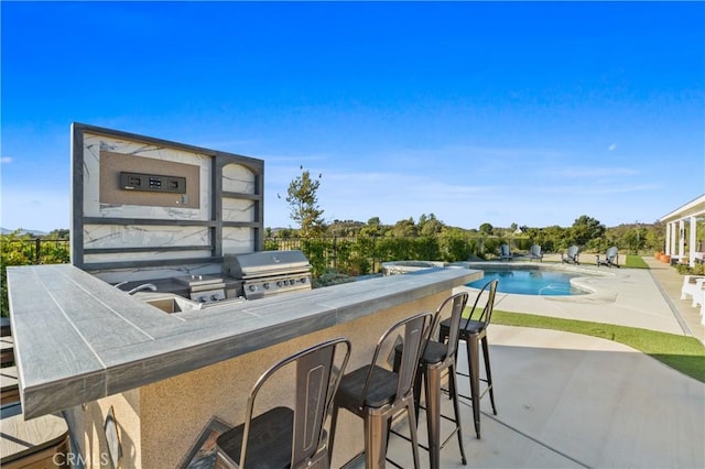 view of patio / terrace with exterior kitchen, a grill, and an outdoor bar