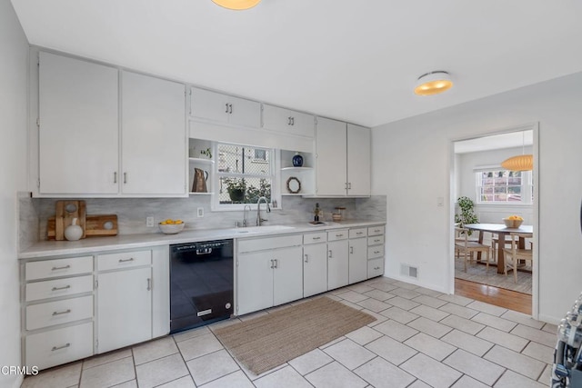 kitchen with sink, white cabinetry, tasteful backsplash, plenty of natural light, and black dishwasher