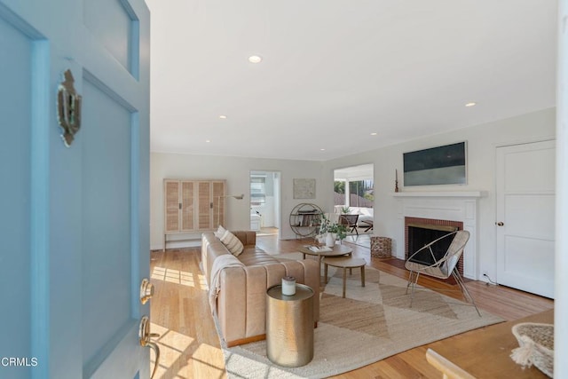 living room with a brick fireplace and light wood-type flooring