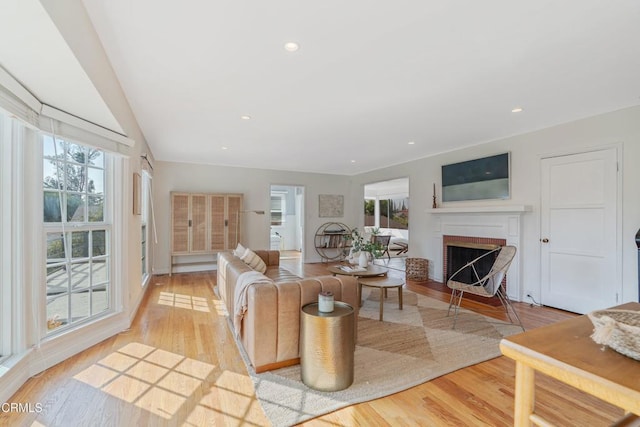 living room with a brick fireplace and light hardwood / wood-style floors