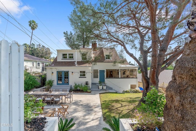 rear view of house with a patio and a lawn