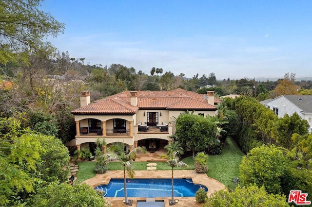 rear view of property with a yard, a patio, and a balcony