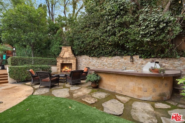 view of patio / terrace featuring area for grilling and an outdoor stone fireplace