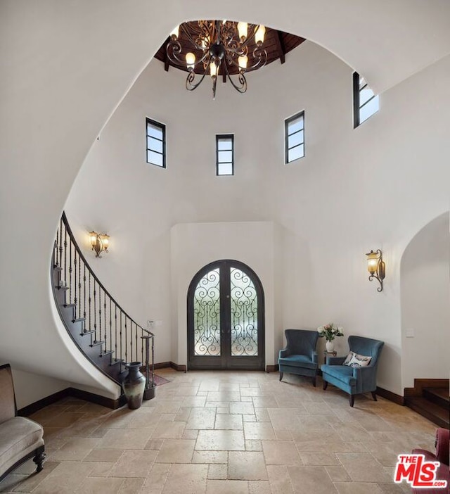 entryway featuring french doors, a chandelier, and a high ceiling